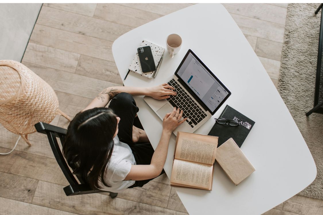 arial shot of person using computer at desk with books