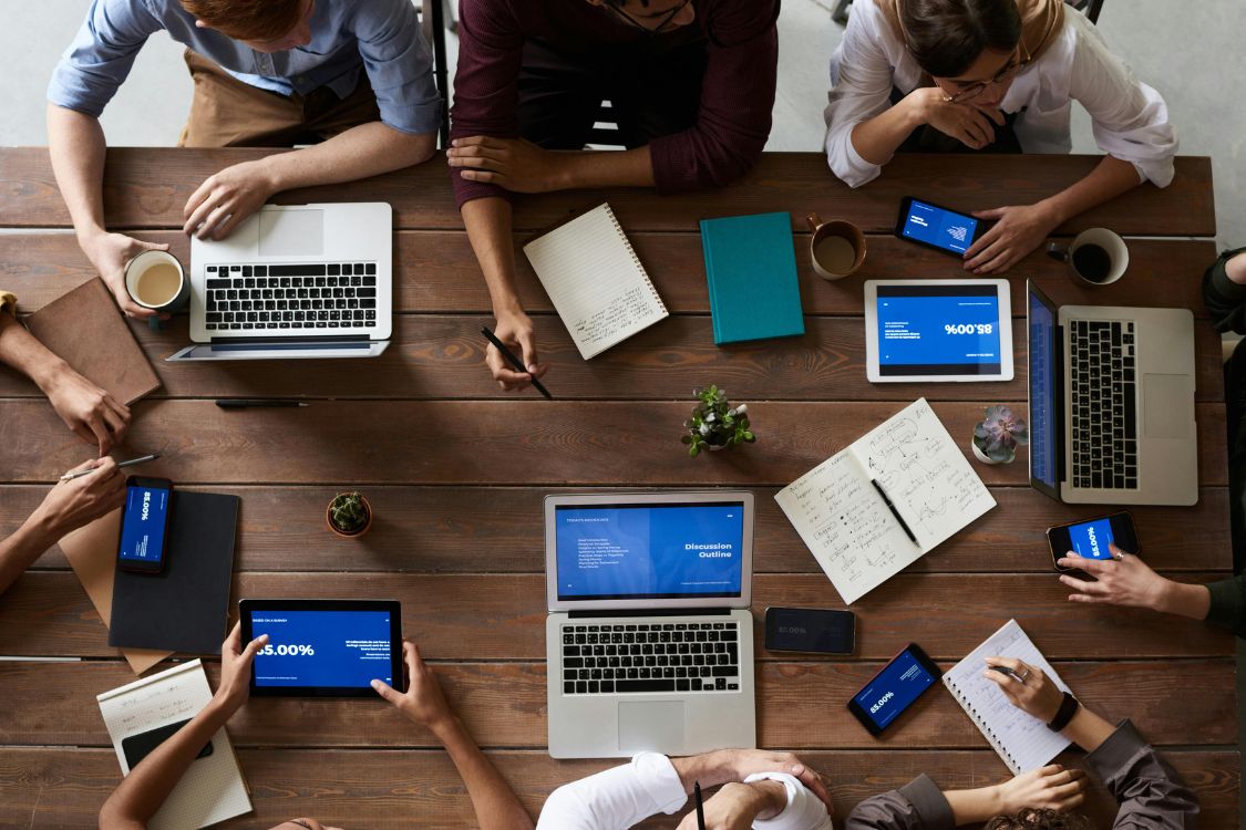 people sitting around table all using a tablet or computer