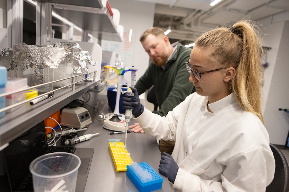 Woman performing a scientific activity with a man looking on