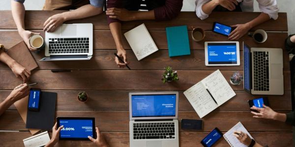people sitting around table all using a tablet or computer