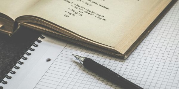 Open book next to pen and paper